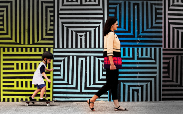 Woman and child walking in front of colorful geometric patterned wall